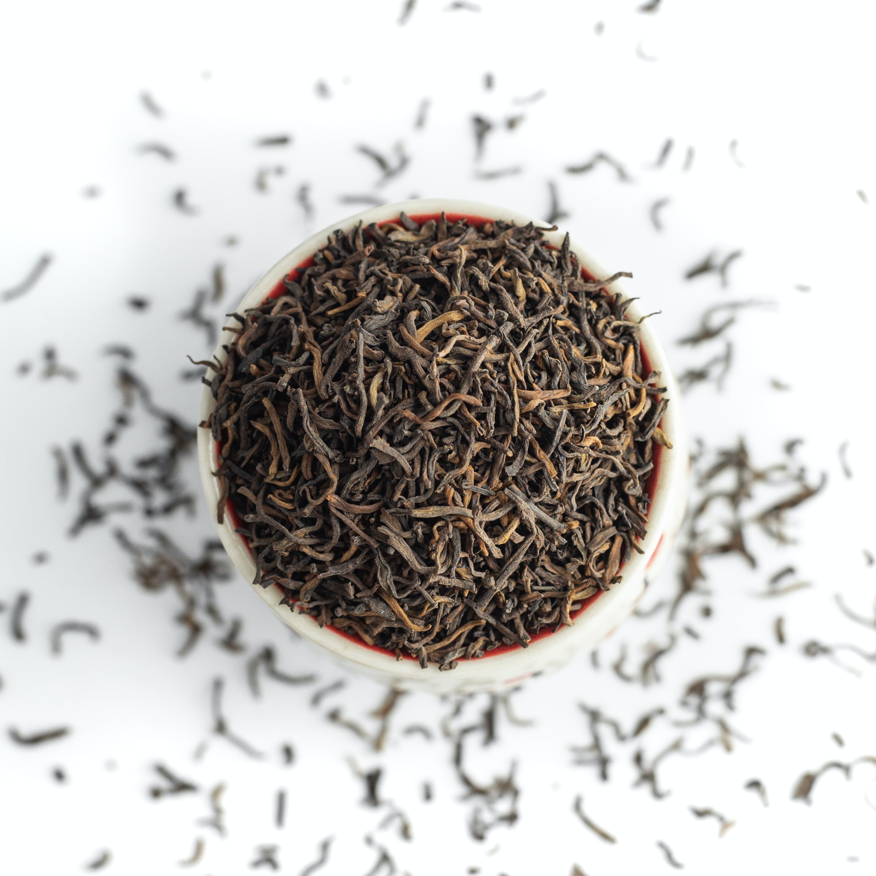 A close-up of tea leaves in a ceramic cup on a solid surface.